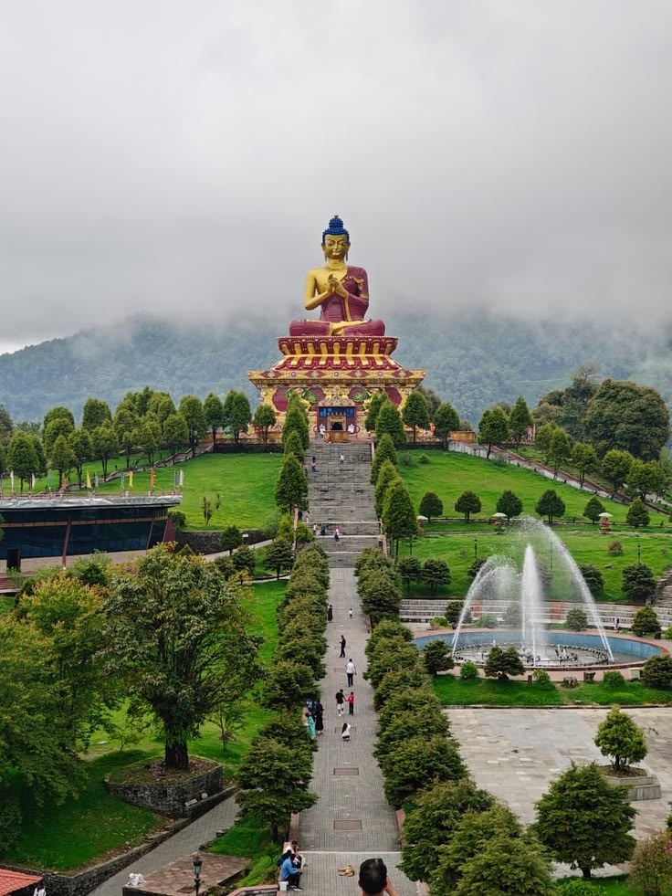 A long straight avenue leading toward a monumental golden Buddha statue in the mist